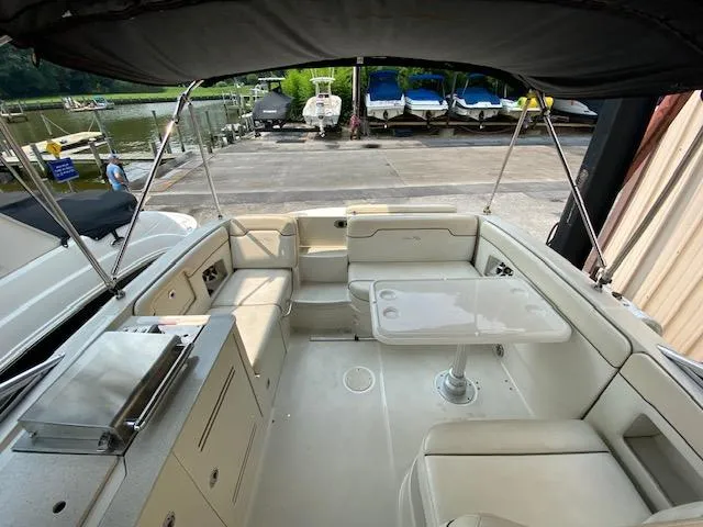 Slide: The Image of 2008 Sea Ray 290 Sundeck boat interior with seating and table, docked near other boats. - 12