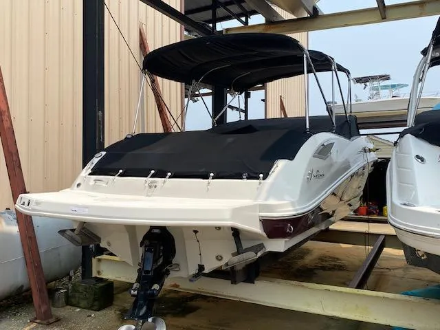 Slide: The Image of 2008 Sea Ray 290 Sundeck boat with black canopy, docked in storage facility. - 2
