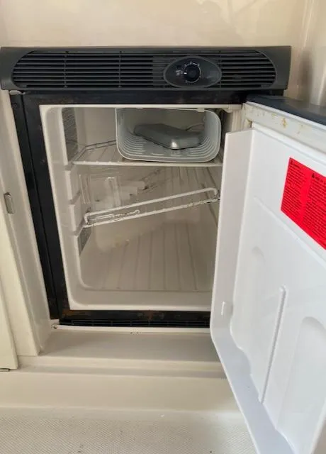 Slide: The Image of Open mini fridge inside 2008 Sea Ray 290 Sundeck boat, showing empty shelves. - 39