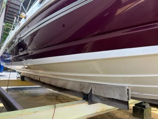 Slide: The Image of 2008 Sea Ray 290 Sundeck boat on a lift, showcasing maroon and white hull. - 8