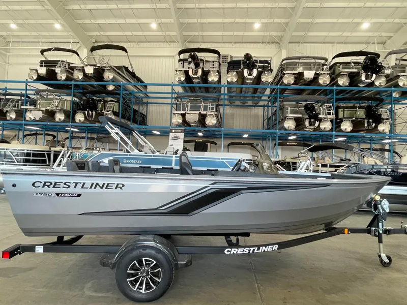 Slide: The Image of 2025 Crestliner 1750 Hawk boat in showroom, surrounded by stacked boats. - 1