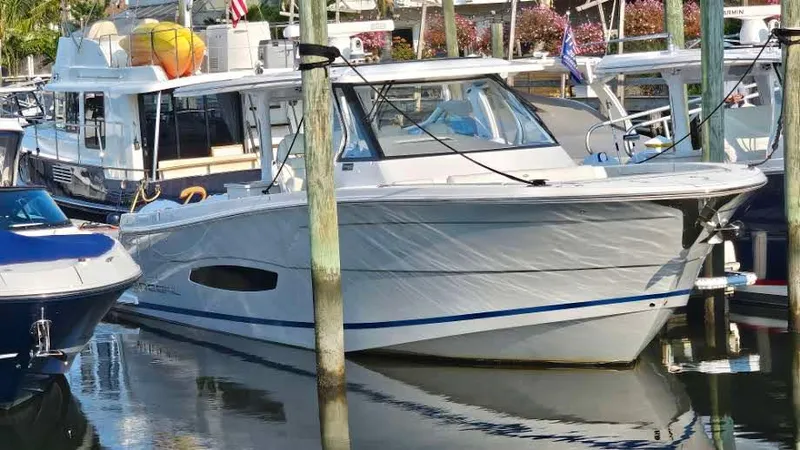 Slide: The Image of 2021 Regal 38 SAV boat docked in a marina, surrounded by other vessels. - 0