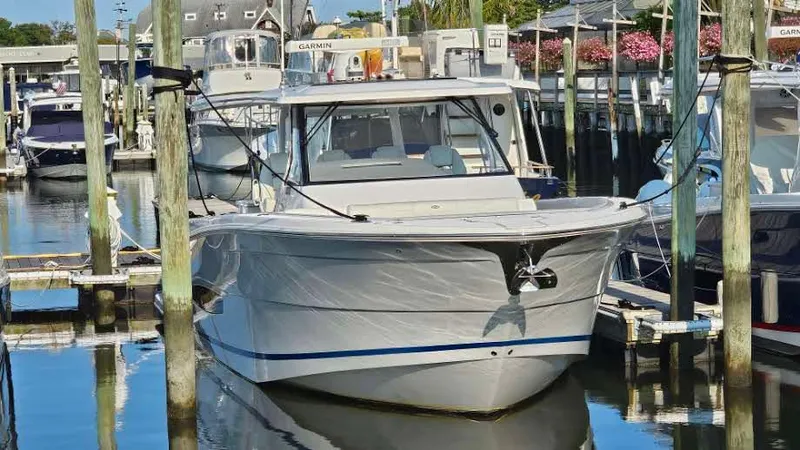 Slide: The Image of 2021 Regal 38 SAV boat docked in a marina, surrounded by other vessels. - 2