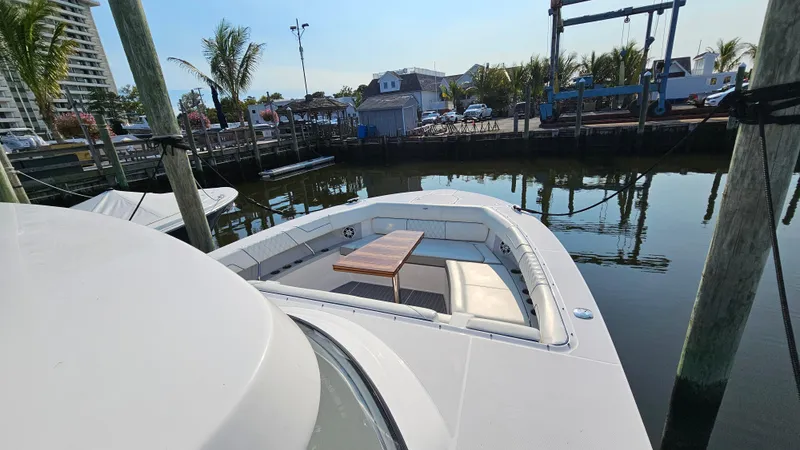 Slide: The Image of 2021 Regal 38 SAV boat docked, featuring spacious seating and table on deck. - 24