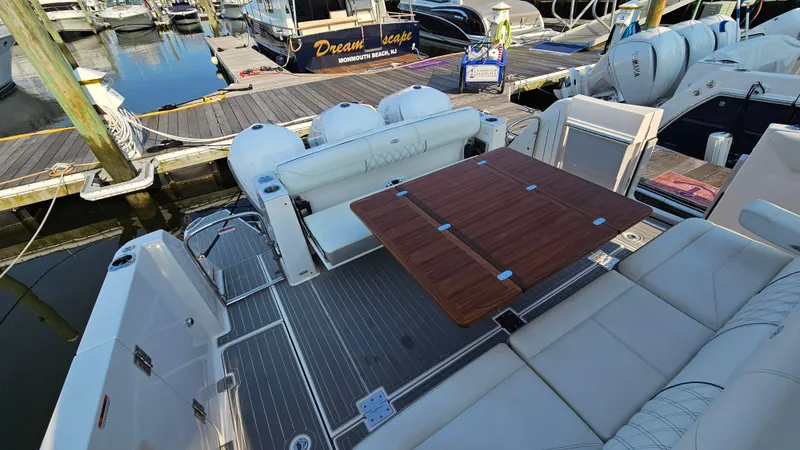 Slide: The Image of 2021 Regal 38 SAV boat interior with seating and wooden table at marina. - 43