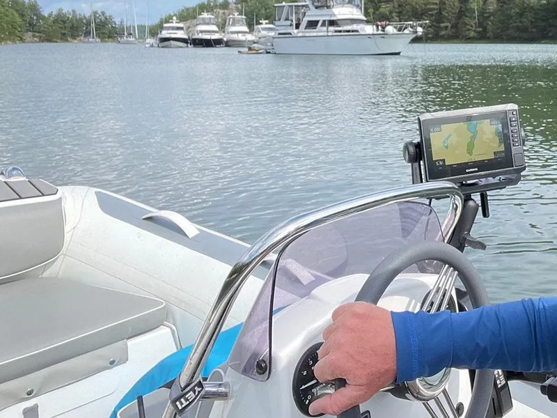Slide: The Image of Person steering a boat with GPS, near docked yachts, including a 2003 Sea Ray 390 Motor Yacht. - 4