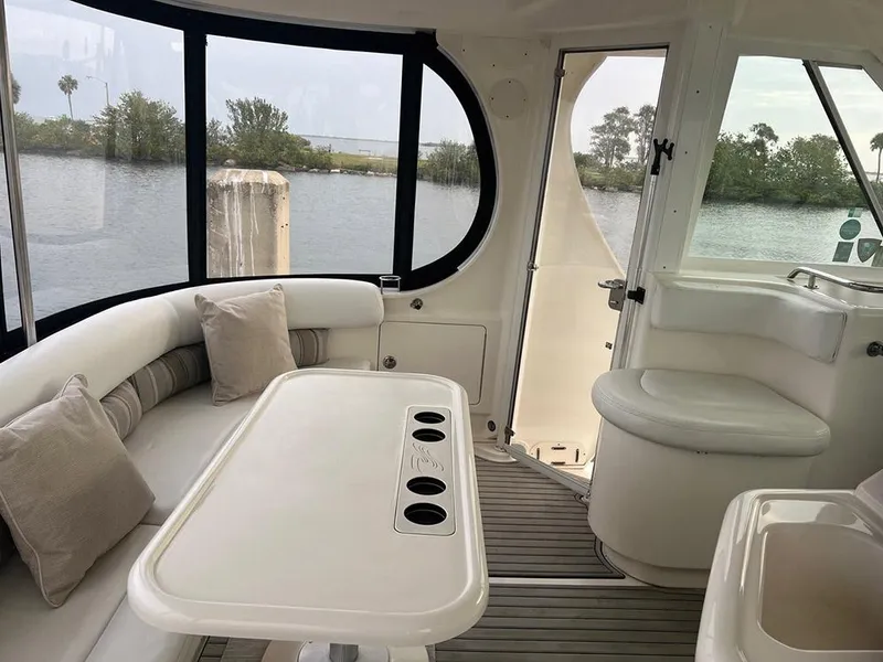 Slide: The Image of 2003 Sea Ray 390 Motor Yacht interior with seating and table, overlooking serene water view. - 52