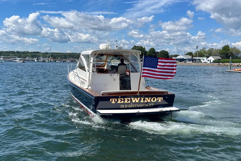 Slide: The Image of 2002 Little Harbor WhisperJet boat on water, American flag, clear sky. - 16