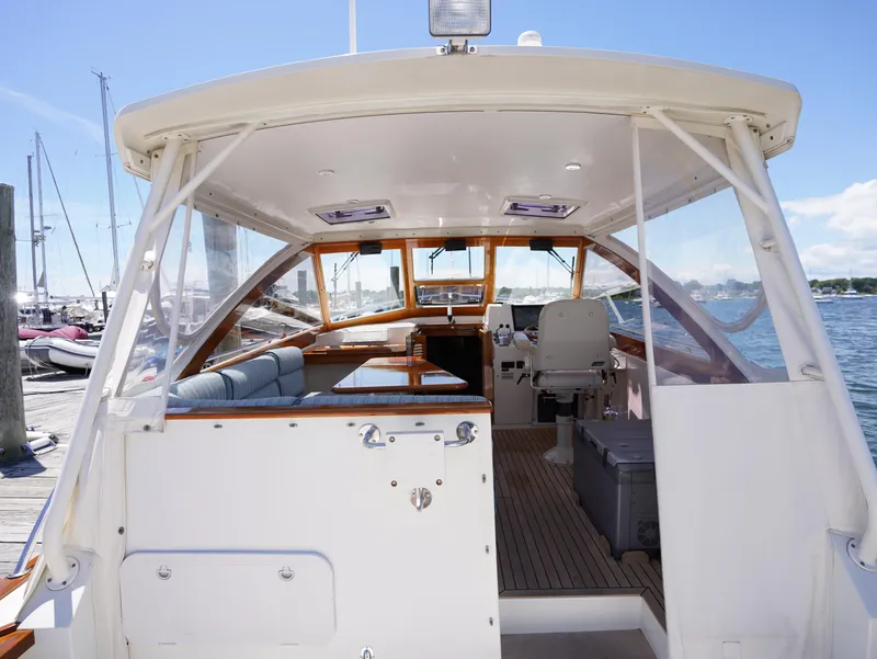 Slide: The Image of 2002 Little Harbor WhisperJet boat interior with seating and helm, docked by the water. - 24