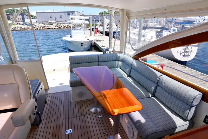 Slide: The Image of Interior of 2002 Little Harbor WhisperJet with plush seating and wooden table by the dock. - 28