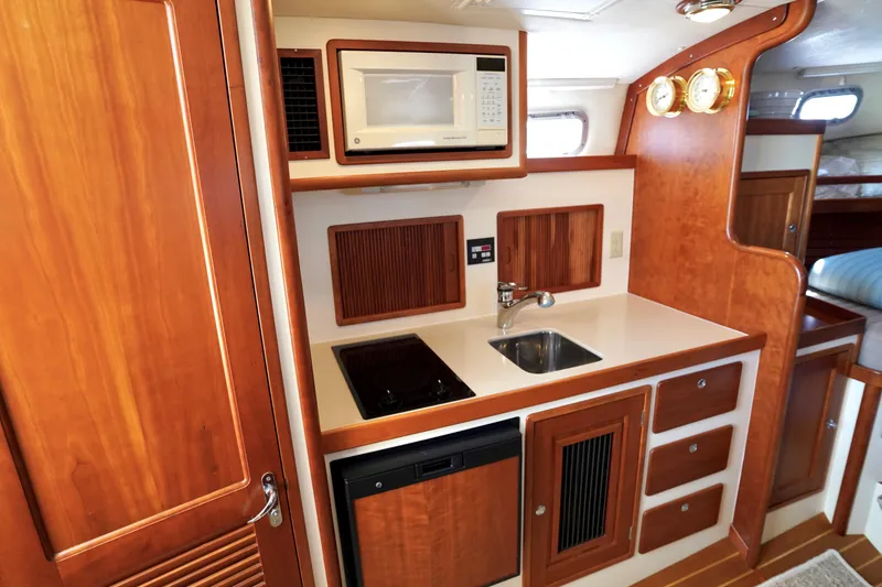 Slide: The Image of 2002 Little Harbor WhisperJet yacht kitchen with microwave, sink, and wooden cabinetry. - 48