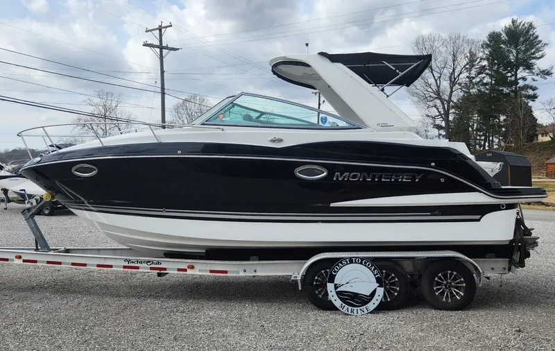 Slide: The Image of 2018 Monterey 275 Sport Yacht on trailer, black and white design, parked outdoors. - 1