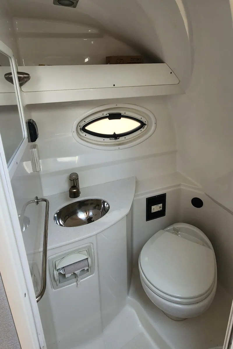Slide: The Image of 2018 Monterey 275 Sport Yacht bathroom with sink, toilet, and porthole window. - 14
