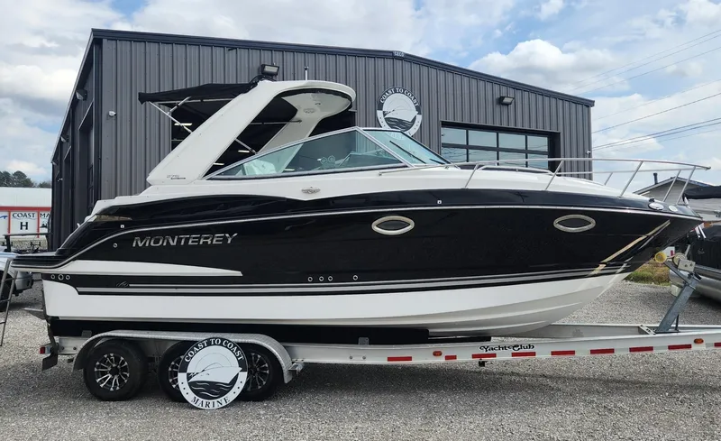 Slide: The Image of 2018 Monterey 275 Sport Yacht on trailer, black and white design, parked outside a building. - 19
