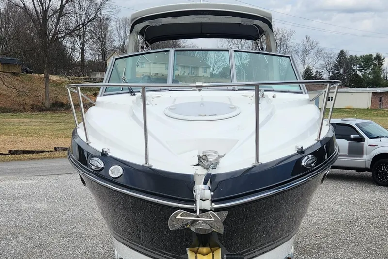 Slide: The Image of 2018 Monterey 275 Sport Yacht, front view, parked on gravel with trees in background. - 2