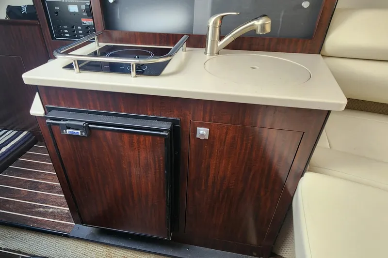 Slide: The Image of Compact kitchenette in 2018 Monterey 275 Sport Yacht with sink, stove, and mini fridge. - 9