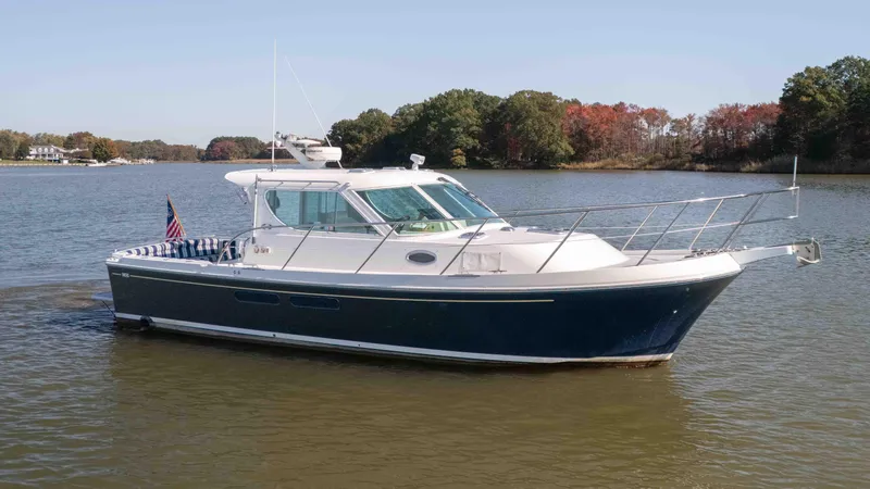 Slide: The Image of 2005 Compton 33 boat on a calm lake with trees in the background. - 3