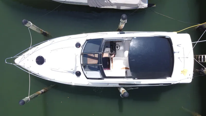 Slide: The Image of 2023 Schaefer 375 HT boat docked, aerial view, sleek design, white hull, black canopy. - 2