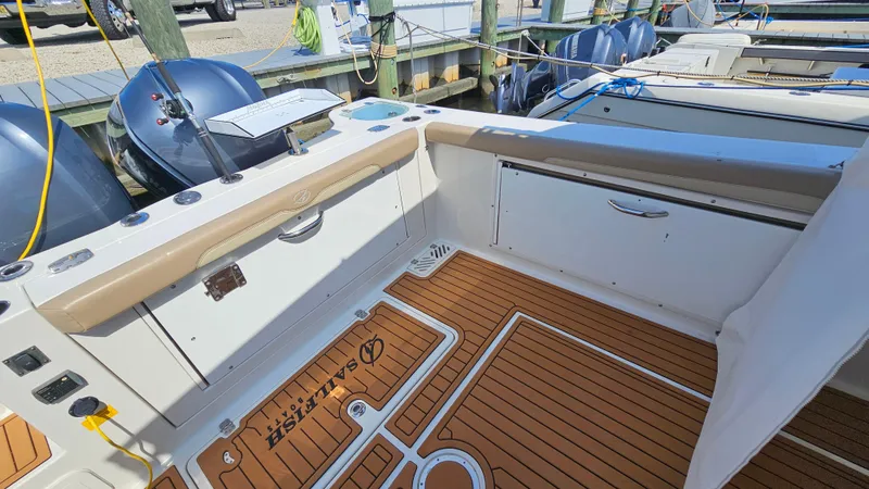 Slide: The Image of 2019 Sailfish 325 DC boat interior with teak flooring and dual outboard motors. - 13