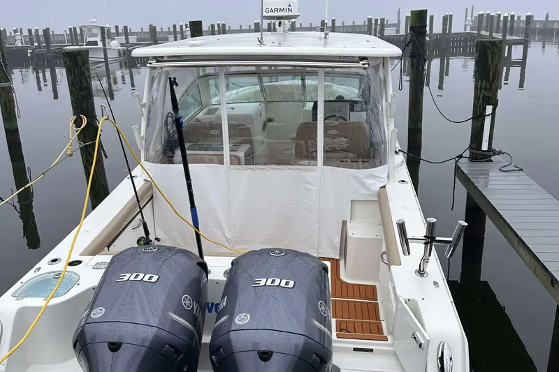 Slide: The Image of 2019 Sailfish 325 DC boat docked with twin 300 engines, misty marina background. - 2