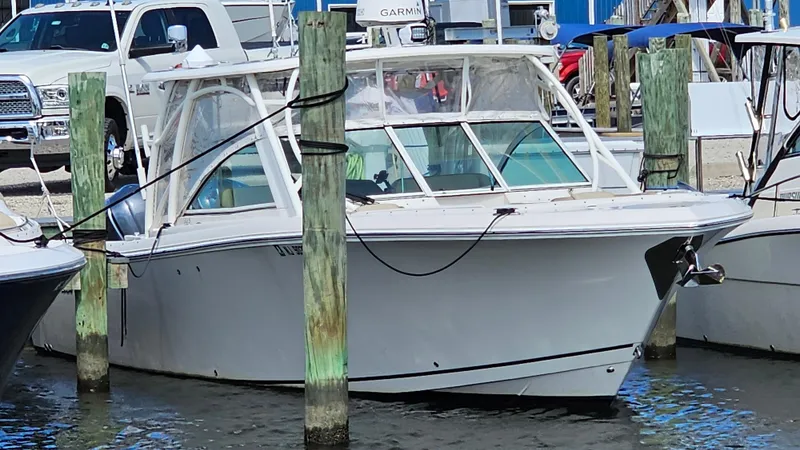 Slide: The Image of 2019 Sailfish 325 DC boat docked at marina with vehicles in background. - 5