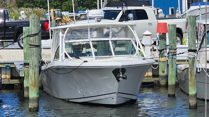 Slide: The Image of 2019 Sailfish 325 DC boat docked at marina with trucks in background. - 7