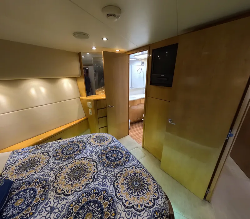 Slide: The Image of Interior of 2001 Hatteras 55 Convertible yacht bedroom with patterned bedding and wooden accents. - 24
