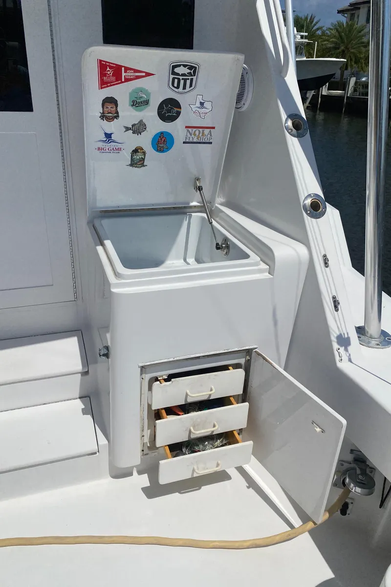 Slide: The Image of 2001 Hatteras 55 Convertible boat with open storage compartments and sticker-decorated lid. - 54