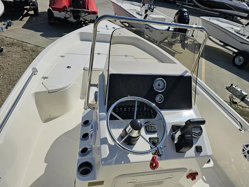 Slide: The Image of 2025 Bulls Bay 2000 boat dashboard with steering wheel and controls, parked in a marina. - 11
