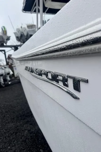 Slide: The Image of 2022 Aquasport 2100 Center Console boat, close-up of logo on white hull. - 13