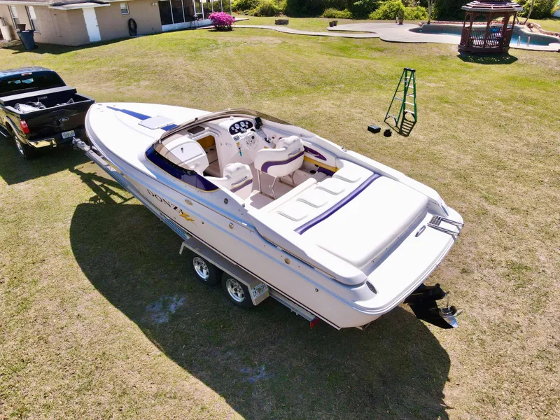 Slide: The Image of 1999 Donzi 26 ZX boat on trailer, parked on grass, near a pickup truck. - 26