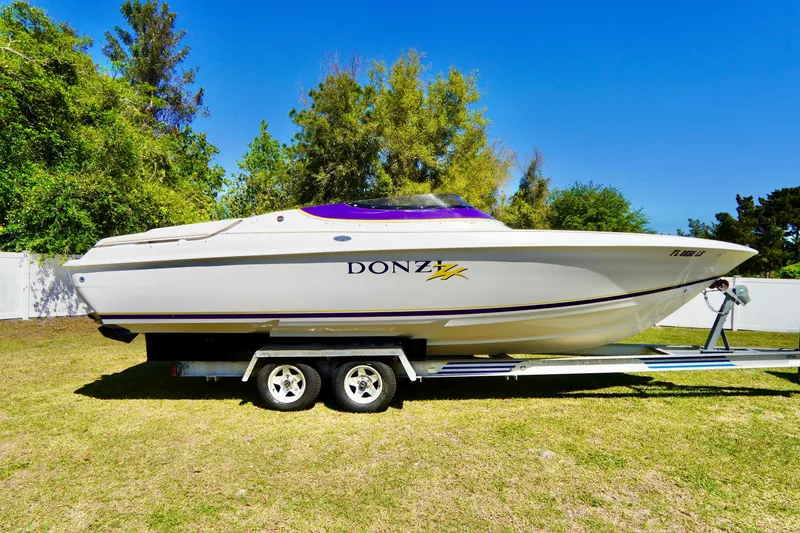 Slide: The Image of 1999 Donzi 26 ZX boat on trailer, parked on grass with trees in background. - 3