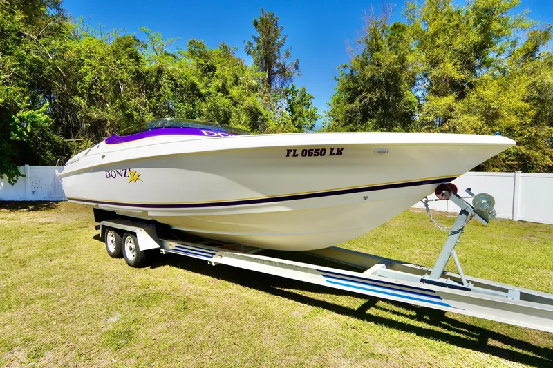 Slide: The Image of 1999 Donzi 26 ZX speedboat on trailer, parked on grass with trees in background. - 4