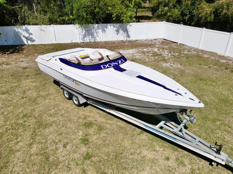 Slide: The Image of 1999 Donzi 26 ZX speedboat on trailer, parked on grass, surrounded by white fence. - 5
