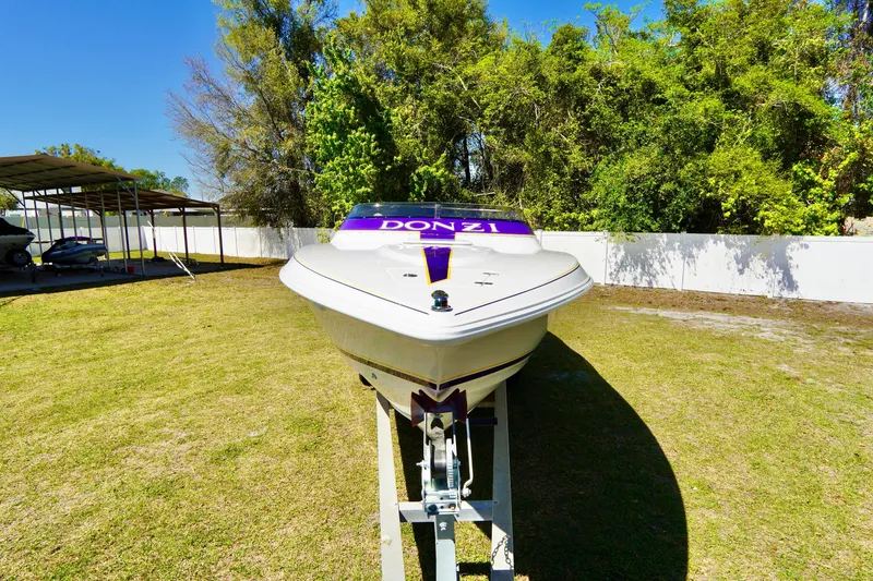 Slide: The Image of 1999 Donzi 26 ZX boat on trailer, parked on grass with trees in background. - 7
