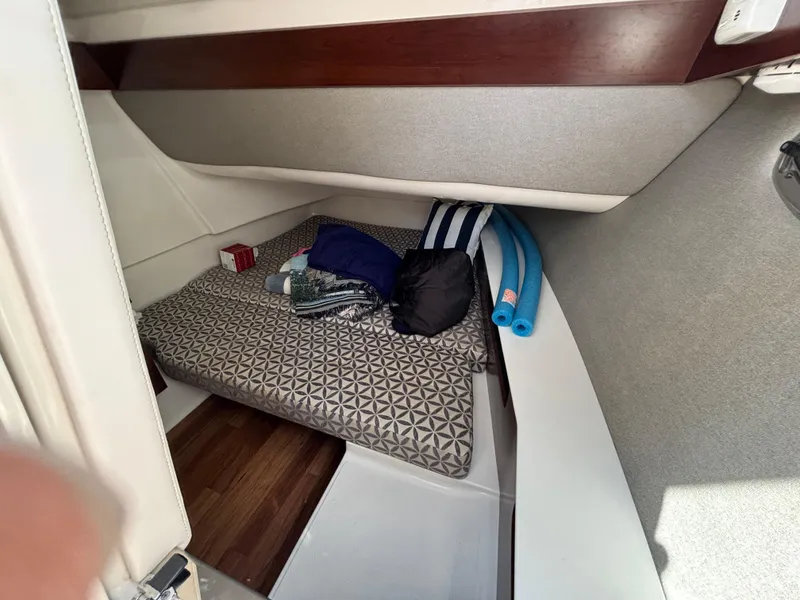 Slide: The Image of 2021 Chaparral 300 OSX cabin interior with bed and storage items. - 10