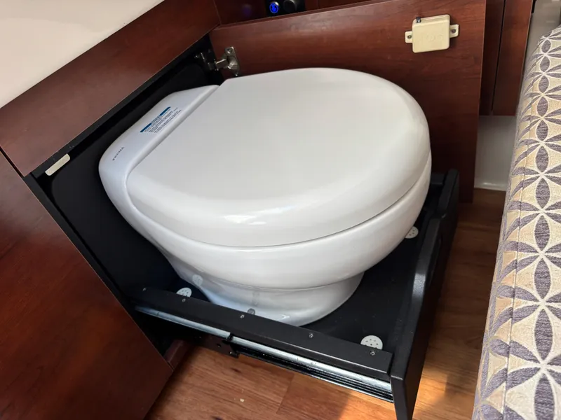 Slide: The Image of 2021 Chaparral 300 OSX boat interior with a compact, pull-out toilet design. - 12