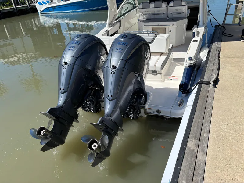 Slide: The Image of 2021 Chaparral 300 OSX boat with dual outboard engines docked in calm water. - 3