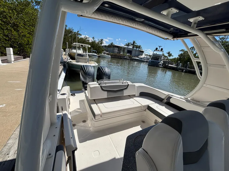 Slide: The Image of 2021 Chaparral 300 OSX boat docked, featuring spacious seating and dual outboard engines. - 4