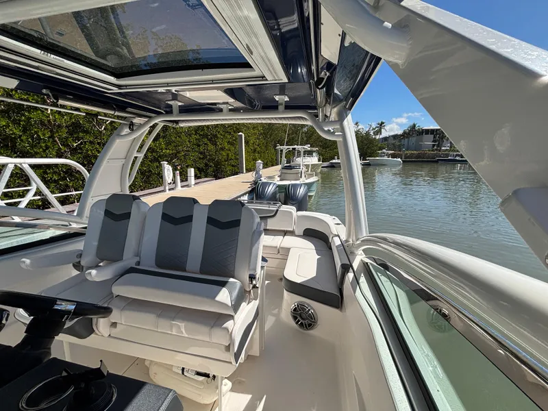 Slide: The Image of 2021 Chaparral 300 OSX boat interior with seating, docked by a serene waterfront. - 6
