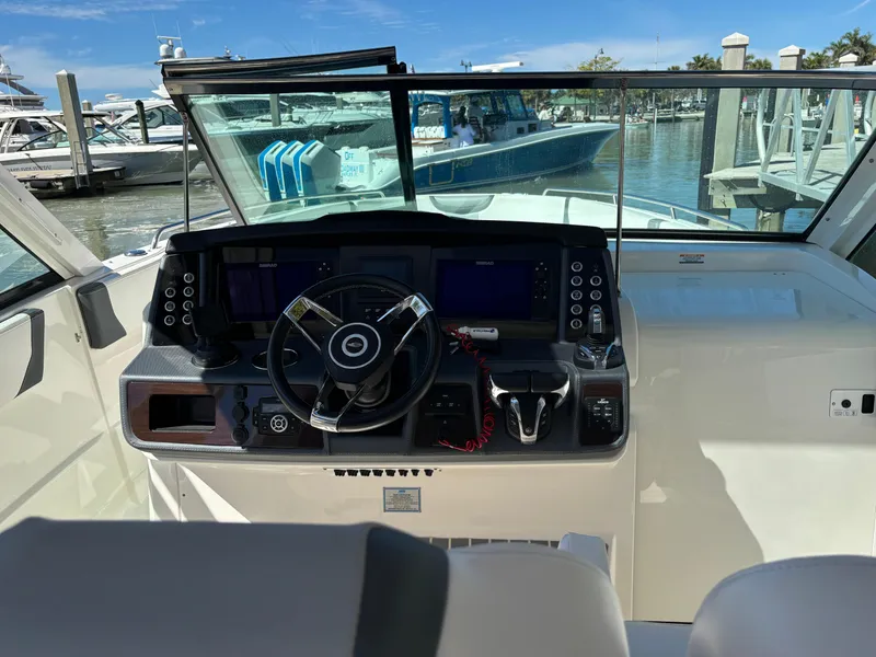 Slide: The Image of 2021 Chaparral 300 OSX boat dashboard with steering wheel and controls at marina. - 7
