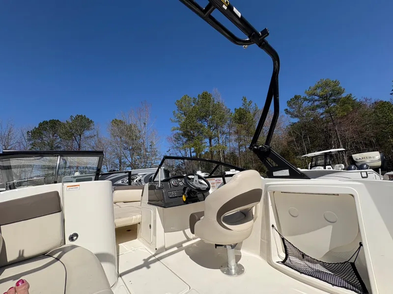 Slide: The Image of 2019 Bayliner 210 Deck Boat interior with seating, steering console, and clear blue sky. - 11
