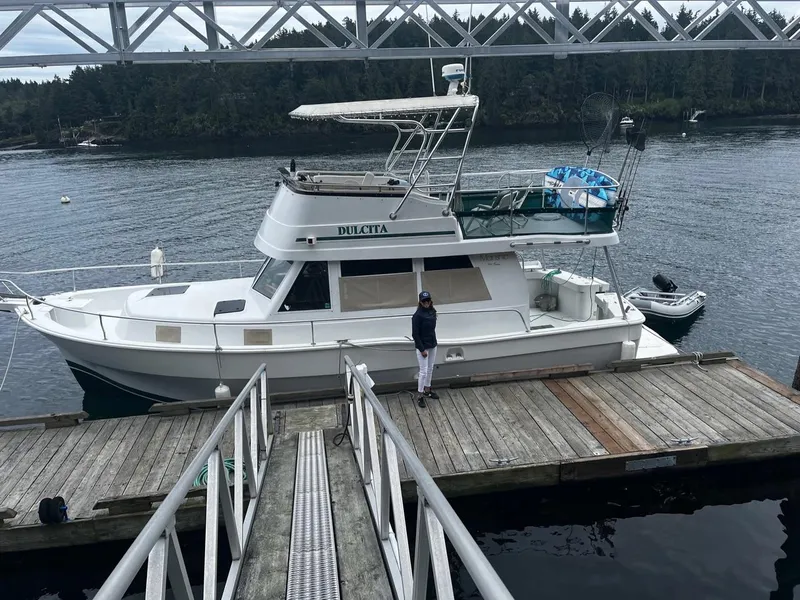 Slide: The Image of 1997 Mainship 350 docked under a bridge, with a person standing on the deck. - 1