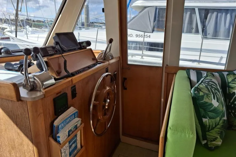 Slide: The Image of Interior of a 1997 Mainship 350 boat with steering wheel and green seating. - 14