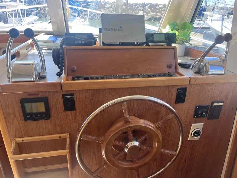 Slide: The Image of 1997 Mainship 350 helm with Garmin navigation, wooden wheel, and dual throttle controls. - 15