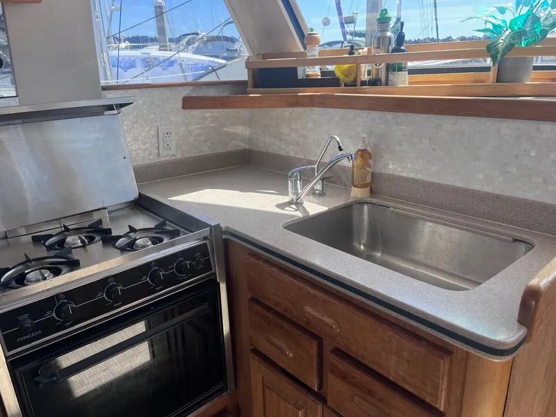 Slide: The Image of 1997 Mainship 350 yacht kitchen with stove, sink, and wooden cabinetry. - 19