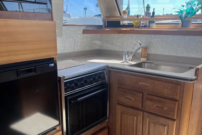 Slide: The Image of 1997 Mainship 350 yacht kitchen with stove, sink, and wooden cabinetry. - 20