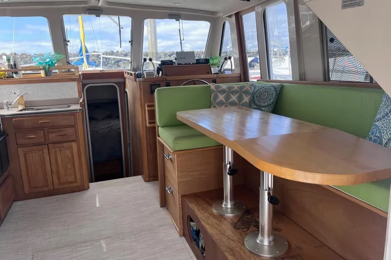 Slide: The Image of Interior of 1997 Mainship 350 yacht with green seating and wooden table. - 21