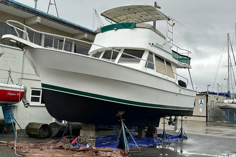 Slide: The Image of 1997 Mainship 350 boat on dry dock, white hull, green accents, overcast sky. - 3