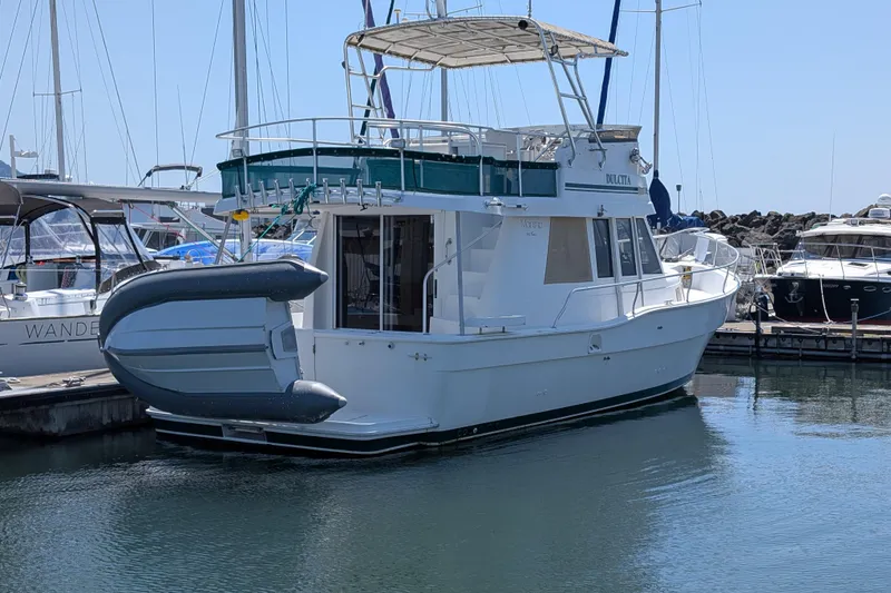 Slide: The Image of 1997 Mainship 350 yacht docked in marina, featuring upper deck and inflatable dinghy. - 33